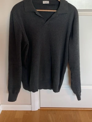 Mörkgrå tröja med krage från John Henric  - Snygg mörkgrå tröja från John Henric med klassisk krage och långa ärmar. Tröjan har en avslappnad passform och ribbade muddar vid ärmslut och nederkant. Perfekt till jeans