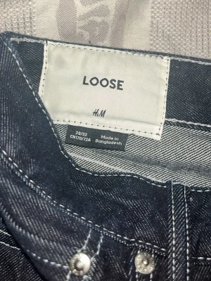 jeans - Säljer ett par svarta loose fit jeans från H&M med kontrastsömmar. Jeansen har rak passform och är tillverkade i kraftigt denimtyg. Perfekta för en avslappnad och trendig stil.