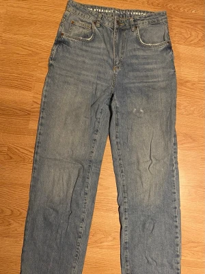 Bik Bok 90’s straight  jeans waist 28 length 32 - Säljer ett par klassiska blå jeans med rak passform och fem fickor. Jeansen har midja 28 och längd 32, med slitningar och ljus tvätt för en avslappnad look. Perfekta till sneakers och hoodie.