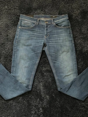 Dondup George - Säljer ett par blå skinny fit jeans från Dondup, modellen George, med klassisk femficksdesign. Jeansen har ljusare tvätt på baksidan och kontrastsömmar. Perfekta för en avslappnad och trendig look.           Midjemått: 41 cm    Längdmått: 103cm