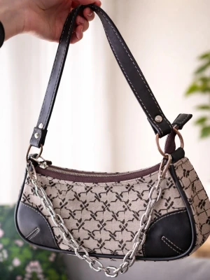 Iets Frans Monogram Buckle Faux Leather Shoulder Bag  - Trendig Iets Frans Monogram Buckle Faux Leather Shoulder Bag. Svarta läderdetaljer i hörnen. Väskan har en bred axelrem i svart konstläder med vita sömmar och en silverfärgad kedja framtill. Stängs med dragkedja och har en stilren, avlång form.