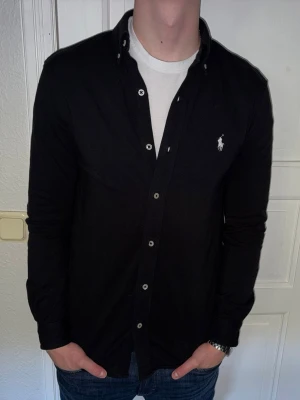Svart skjorta från Ralph Lauren - Svart skjorta från Ralph Lauren i storlek S.  Fint skick till ett bra pris. Nypris: 1995kr. Mitt pris: 349kr. Vid frågor eller funderingar, tveka inte att höra av dig.