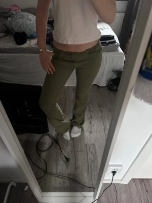 Olivgröna low waist jeans med rå kant - Säljer ett par olivgröna low waist jeans med rå kant i midjan och raka ben. Jeansen har en avslappnad passform och cool vintage vibe, perfekta till crop tops eller hoodies. Materialet känns mjukt och stretchigt för extra komfort.