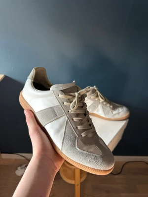Maison margiela gats - Maison Margiela GAT säljes i storlek 42. Skorna är i jättebra skick överlag och väldigt välbevarade. Enda lilla defekten är att loggan på tungan har fadat lite på grund av snörena men det syns inte vid användning. Annars är skorna i riktigt fint skick. Säljer dem pågrund av att dom dem var lite för stora. Priset är ej hugget i sten!!