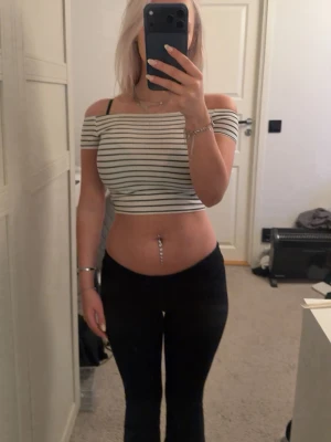 Randig offshoulder topp - Säljer en vit croppad topp med svarta ränder och offshoulder-design från H&M i storlek 146-152. 