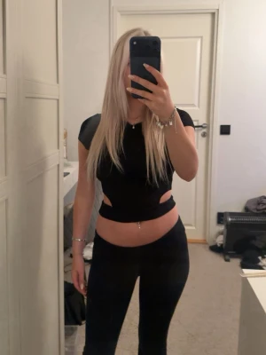 Svart topp med cut-outs - Säljer svart croppad topp med cut-outs på sidorna från Stradivarius i storlek XS.