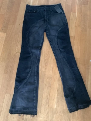 Svarta bootcut jeans med vågiga sömmar - Säljer ett par svarta bootcut jeans med unika vågiga sömmar storlek 30 men hade sagt en 28/29