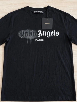 Svart Palm Angels t-shirt Paris - Svart t-shirt från Palm Angels med tryck i vitt och grått framtill där det står 'Palm Angels Paris'. Klassisk passform med rund hals och korta ärmar. Materialet är mjuk bomull, perfekt för en streetwear-look.