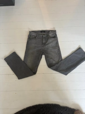 Grå raka jeans från Replay - Snygga grå jeans från Replay med klassisk femficksdesign och raka ben. Jeansen har en diskret tvättad look och svarta detaljer vid knappar och nitar. Perfekta för en avslappnad och trendig stil. Köpt för 100 och säljer för 250 passar folk till 158- 172