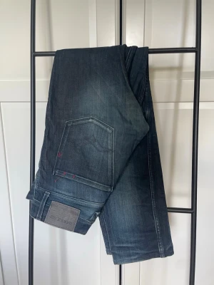 Mörkblå replay anbass jeans  - Säljer ett par snygga replay anbass jeans med en väldigt unik och snygg tvätt. Jeansen är i storlek 33/34 på lappen men stämmer inte överens med verkligheten. De är mer som 30/32 och är 5 centimeter mindre på bägge sidor i midjan ( se de sista bilderna) på de sista bilderna är ett par som egentligen är i storlek 33/34 från replay som man kan jämföra med. Vid frågor eller funderingar hör av er. 