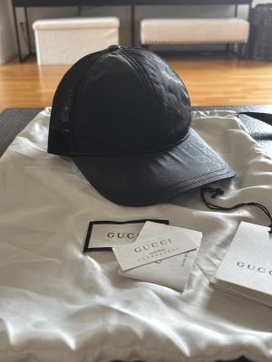 Gucci keps svart - Gucci keps nylon storlek M den är i bra skick man får med dustbag lappar osv. Det är bara två knappar på den kvar, går att fixa hos skräddaren 