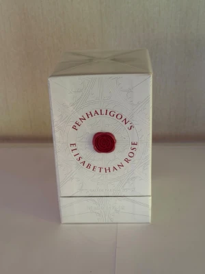 Penhaligon's Elisabethan Rose parfym - Penhaligon's Elisabethan Rose är en exklusiv parfym i en elegant vit kartong med detaljer i rött och silver. Förpackningen har en klassisk, lyxig känsla och rymmer 100 ml Eau de Parfum. Perfekt för dig som gillar rosdoft och stilrena designer.