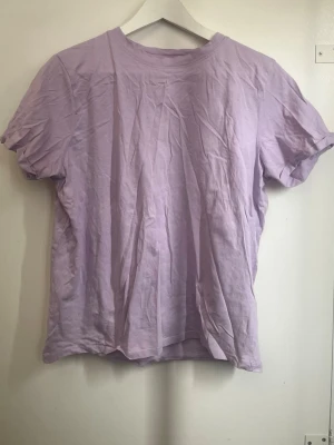 Ljuslila basic t-shirt - En enkel och stilren ljuslila t-shirt med rund hals och korta ärmar. Perfekt för en avslappnad look och lätt att matcha med andra plagg. 