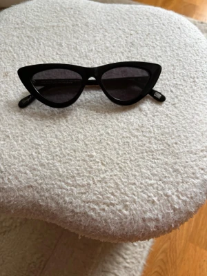 Svarta cat eye solglasögon - Snygga svarta solglasögon i klassisk cat eye-modell med svarta bågar och mörka glas. Perfekta för att ge din look en trendig och cool touch. Passar dig som gillar att sticka ut med accessoarer.