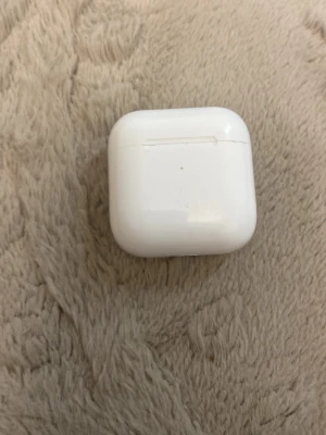 Vita trådlösa hörlurar Apple AirPods - Säljer ett par vita Apple AirPods med laddningsetui. Snygg och smidig design i blank plast, perfekt för dig som vill ha trådlös frihet och bra ljud till mobilen eller datorn. Laddningsfodralet är kompakt och lätt att ta med överallt.