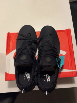 Svarta Nike Air Presto sneakers - Svarta Nike Air Presto sneakers med stilren design och diskreta detaljer. Ovandel i mesh och syntet för en luftig känsla, med klassisk Nike-logga på sidan och tungan. Sulan är svart och ger bra dämpning. Perfekta för dig som gillar sportig och clean stil.