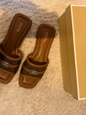 Bruna sandaler från Michael Kors - Jätteeleganta bruna sandaler från Michael Kors som endast är använda två gånger, därav baksidan. Annars som helt nya. Nypris 1695kr! 