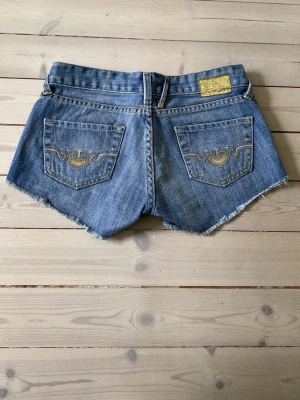 Blå jeansshorts med rå kant - Säljer ett par blå jeansshorts från Cross jeans då de tyvärr är för små. De är i väldigt gott skick, dock är lite av färgen borta på knappen som man kan se på bilden. Perfekta inför sommaren🌸☀️