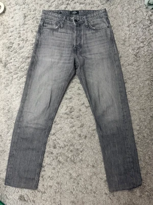 Grå relaxed jeans från Jack & Jones - Snygga grå jeans från Jack & Jones i relaxed fit-modell. Jeansen har fem klassiska fickor, raka ben och en cool tvättad look. Perfekta för en avslappnad stil och lätta att matcha med olika outfits.