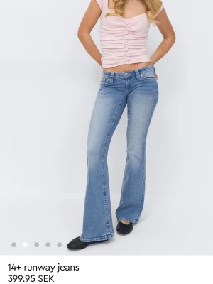 Blå bootcut jeans Gina young  - Snygga ljusblå bootcut jeans från 14+ med klassisk femficksdesign och broderad detalj på bakfickorna. Jeansen har låg midja och utsvängda ben, perfekta för en trendig och avslappnad look. Tillverkade i denim med lätt stretch för extra komfort.