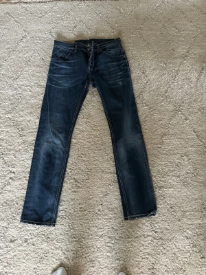 Mörkblå Dondup jeans med slitningar  - Snygga mörkblå jeans med raka ben och diskreta slitningar framtill. Jeansen har klassisk femficksdesign, kontrastsömmar och dragkedja. Perfekta för en avslappnad och trendig look. Dondup storlek 34, men passar även 33 och 32. Det är jättebra skick. Inga skador eller defekter. Priset kan diskuteras