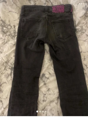 Svarta jeans från Cheap Monday - Säljer ett par svarta jeans från Cheap Monday med klassisk femficksmodell och smal passform. Jeansen har en lila logotyp-patch bak i midjan och är tillverkade i stretchigt denimtyg för extra komfort.