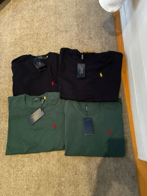 Grön och svart t-shirt från Polo Ralph Lauren - Klassisk grönoch svart  t-shirt från Polo Ralph Lauren med rund halsringning och korta ärmar. T-shirten har den ikoniska broderade loggan i rött på bröstet och är tillverkad i mjuk bomull. Perfekt för en stilren och avslappnad look. Storleken Är lite Liten i tröjan står det L men jag skulle säga M-L. Passar bra för kvinnor fast det är Man tröja