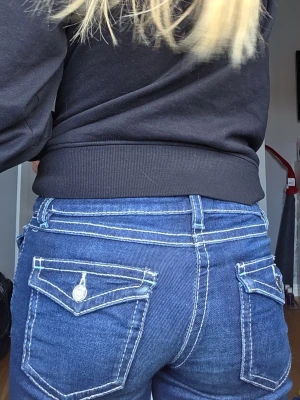 Mörkblå jeans med vita sömmar från gina tricot. - Säljer ett par mörkblå jeans med tydliga vita kontrastsömmar och klassiska fem fickor. Jeansen har låg midja och utsvängda ben. Snygga detaljer på fickorna och silverfärgade knappar. Perfekta för en trendig och avslappnad stil.