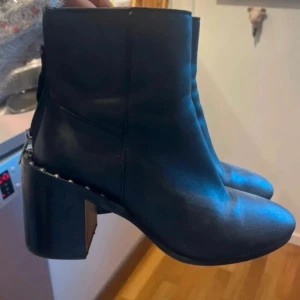 Svarta boots med klack och nitar storlek 37 - Säljer ett par ankelstövlar / boots i storlek 37.   Använd vid ett tillfälle, jättefint skick! Nitar och dragkedja bak på vaden. Äkta Skinn.   Köpt på ASOS. 
