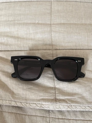 Svarta solglasögon Chimi Core 04 - Snygga svarta solglasögon från Chimi, modell Core 04. De har en klassisk, lite kantig form och är tillverkade i blank svart acetat med mörka glas. Säljer för att jag inte använder, helt oanvända.