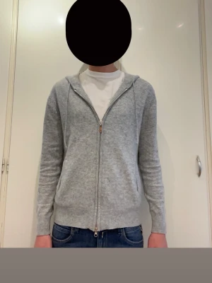 Merinoull zip hoodie  - Grå merinoull hoodie från märket Zadolo. Storlek xs. Jag på bilden är 171 cm lång och den är lite liten för mig. Två zippers på dragkedjan, se bild 6. Taggen i nacken är lite missfärgad men annars är tröjan helt defekt fri. Skriv gärna vid minsta fundering.