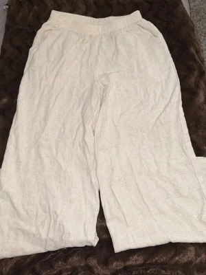 Beiga linnebyxor från SHEIN - Snygga och luftiga beiga linnebyxor från SHEIN i storlek M. Byxorna har resår i midjan och raka, vida ben. Perfekta för en avslappnad och trendig stil. Tillverkade i ett lätt och svalt linnematerial.