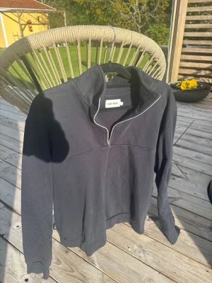 Marinblå half zip-tröja från East West - Svart långärmad tröja från East West med half zip-dragkedja och hög krage. Perfekt för en avslappnad och stilren look. Tröjan har en enkel design och är lätt att matcha med andra plagg.