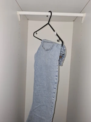 Ljusblå raka jeans i klassisk modell - Säljer ett par ljusblå jeans med rak passform och klassiska fem fickor. Jeansen har hög midja och är tillverkade i denim. Perfekta för en avslappnad och trendig look. 146