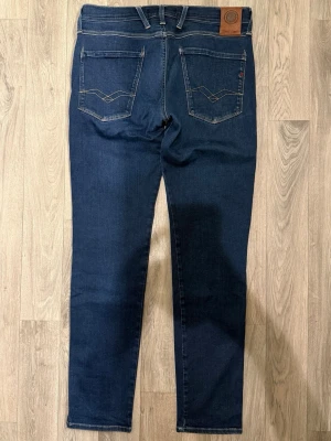 Replay Anbass Hyperflex Dry Jeans Mörkblå W32/L32 - Slim Fit - Replay Anbass Hyperflex Dry mörkblå jeans i stretchig Hyperflex denim med slim fit passform som sitter snyggt och bekvämt och funkar till allt, storlek W32/L32, midja 41,5 cm, ytterbenslängd 103,5 cm, benöppning 15,5 cm, modellen är 185cm & väger 65kg, i fint skick.