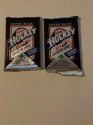 NHL Hockey 1990-91 samlarkortpaket - Två oöppnade paket NHL Hockey Collector Cards från 1990-91, Premiere Edition. Varje paket innehåller 12 samlarkort. Förpackningarna är svarta med silverdetaljer och tydlig logga. Perfekt för dig som gillar hockey och samlarkort.
