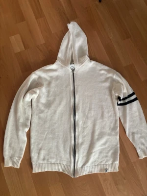 Vit peregrine hoodie med svart detalj  - . Tröjan är för kort för mig både i ärm och kropp därav säljs den / underbar fräsch hoodie inför sommaren som passar till det mesta och är tunn och luftig perfekt till varmare väder står stl L men sitter som en M inte mer. Använd 5 ggr pga för liten efter första tvätten 