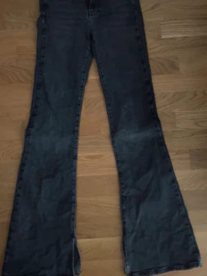 Svarta bootcut jeans från Gina Tricot - Snygga svarta bootcut jeans från Gina Tricot med klassisk femficksdesign och dragkedja. Jeansen har utsvängda ben och är tillverkade i stretchigt denimtyg för en bekväm passform. Perfekta för en trendig och avslappnad look.
