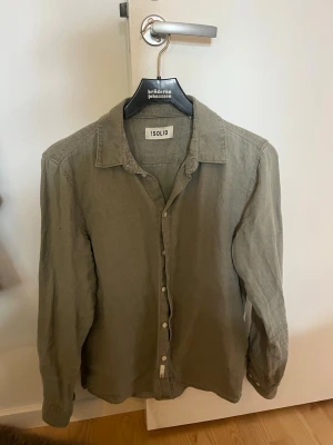 Olivgrön linneskjorta från Solid - Stilren olivgrön skjorta från Solid i linne. Skjortan har klassisk krage, knäppning framtill och långa ärmar. Perfekt för en avslappnad men snygg look.