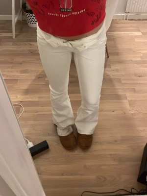Vita bootcut jeans - Säljer ett par vita bootcut jeans. Jeansen har medelhög midja och är tillverkade i ett stretchigt jeans material som sitter snyggt. Knappar på bakfickorna. Säljer pga för korta. Liten fläck på höger bakben💕