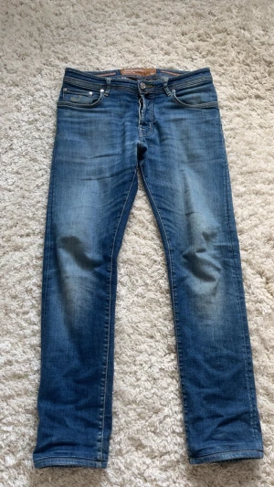 Limited edition Jacob Cohen  - Snygga blå jeans från Jacob Cohen med klassisk femficksdesign och raka ben. Jeansen har en mellanblå tvätt med diskreta slitningar och läderpatch med logga bak i midjan. Jeansen är lite slitna vid ljumsken och har ett lagat hål i fickan.🙌 Perfekta för en avslappnad och trendig look. Nypris ca 10000kr, hör av dig om du har frågor🙌