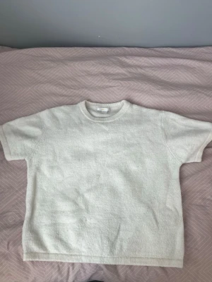 Vit stickad topp från Gina Tricot - Säljer en enkel och snygg vit stickad topp från Gina Tricot. Den har korta ärmar och rund halsringning med ribbade detaljer. Perfekt för dig som gillar en clean och stilren look. Passar dig som vill ha något mjukt och bekvämt.