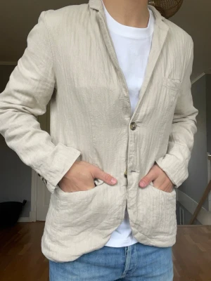 Beige linnesakko / overshirt – Lindbergh White – Slim Fit - Säljer en riktigt clean linnesakko från Lindbergh White 🤍 Perfekt blandning mellan avslappnat och uppklätt — funkar lika bra över t-shirt som skjorta.  • Märke: Lindbergh White • Modell: Slim Fit • Material: Cotton Linen • Färg: Beige / sand • Två fickor framtill + bröstficka • Lätt och luftig passform • Väldigt snygg till sommaren och semestern • Fint skick  Ger en riktigt nice old money / riviera-look tillsammans med ljusa jeans eller eller linnebyxor ☀️💰 Pris: 199kr