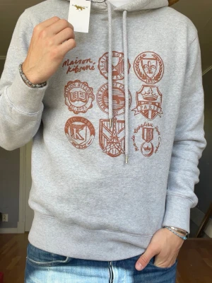 Maison Kitsuné hoodie – Strl S – med tags - Säljer en riktigt clean Maison Kitsuné hoodie i ljusgrå färg med snyggt Paris/Tokyo-print framtill 🔥 Sjukt bra kvalitet och premium känsla som vanligt från Kitsuné.  • Märke: Maison Kitsuné • Storlek: S • Färg: Grå • Tags kvar • Broderade/snörade detaljer i metall • Oversized/relaxed fit • Väldigt bra skick  Perfekt hoodie till både casual och clean outfits 👌 Nypris ligger betydligt högre.  💰 Pris: 999kr 📍 skickas