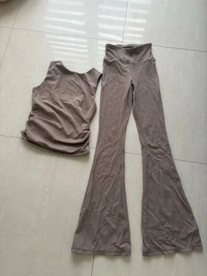 Beiget set med linne och utsvängda byxor - Beige tränings sett från Primark. Otroligt skönt material och knappast använt. Byxorna är högmidjade! 