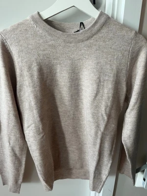 Beige stickad tröja från RYVLS - Mysig beige stickad tröja från RYVLS med rund halsringning och ribbade muddar. Enkel och stilren design som passar perfekt till lager-på-lager-look. Tröjan är mjuk och skön, perfekt för kyligare dagar. 499 nypris för liten. Aldrig använd 