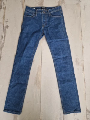 Blå skinny jeans från Crocker - Säljer ett par klassiska blå skinny jeans från Crocker med fem fickor och normal midja. Jeansen har snygga kontrastsömmar och är tillverkade i stretchigt denim för en bekväm passform. Perfekta till din vardagsstil! Strolek 28 32