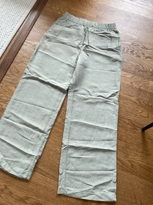Ljusgröna linnebyxor H&M - Snygga ljusgröna linnebyxor med avslappnad passform och resår i midjan samt dragsko. Byxorna har raka ben och sidfickor, perfekta för en chill och luftig stil. Tillverkade i linne för en skön känsla. Passar mig som är 177 cm lång.