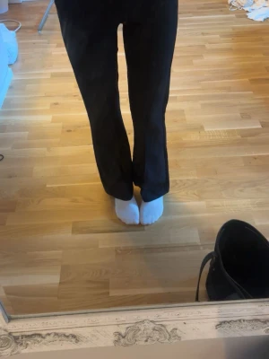 Svarta utsvängda kostymbyxor - Säljer ett par svarta kostymbyxor med utsvängda ben och mellan midja. Byxorna har en klassisk look och är perfekta för en stilren outfit. Materialet är mjukt och stretchigt, vilket ger en snygg passform. De är för korta och därför säljer jag dom, jättesköna byxor som självklart tvättas innan jag skickar dom💖