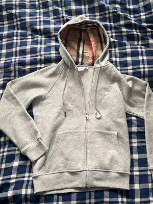 Burberry hoodie  - 1:1 (skriv och fråga om du ej vet vad det innebär) min lillebror blev lurad på denna hoodie så hjälper honom att få tillbaka någon krona nu, den är i storlek M junior vilket bör motsvara XS men utgå från måtten. Bred mellan armhålorna 46cm, längd från högsta axelpunkt 58cm. Längd från armhåla till slut av ärm 49cm.  Skicket är som nytt.